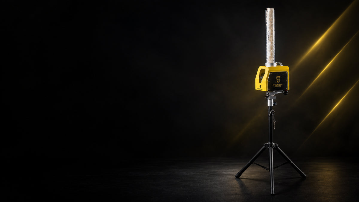BaddyBot Pro badminton shuttle feeder with a full shuttle magazine on its tripod, against a dark background with yellow light streaks.